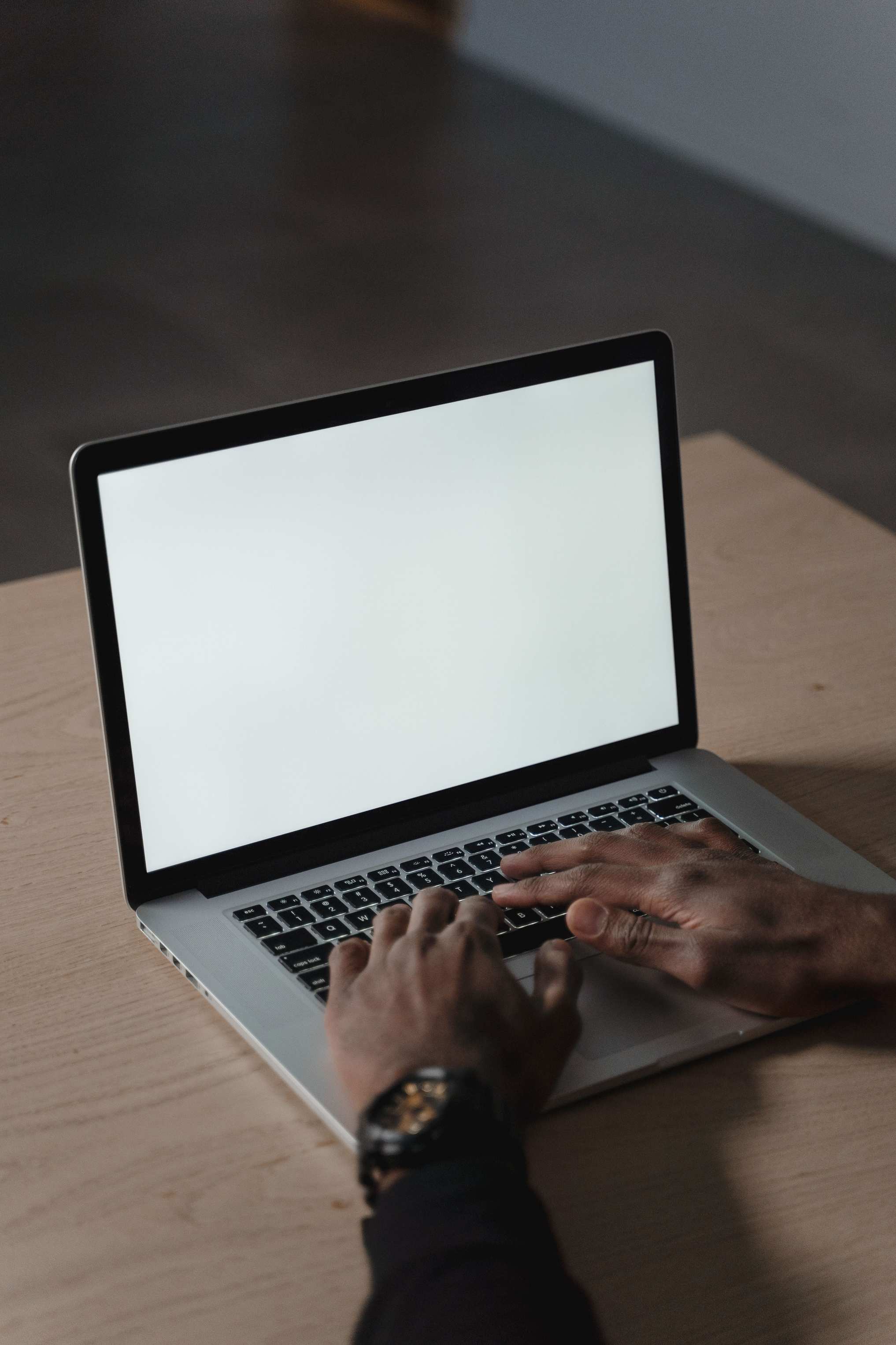 Hands typing on a laptop keyboard at a desk